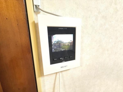 壁に設置されたモニター付きインターホンが確認できます。訪問者の映像を室内から確認できる仕様です。シンプルなデザインで使いやすさにも配慮されています。モニター画面は見やすい位置に配置されています。