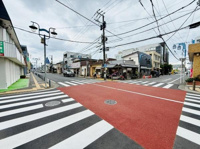 交差点の視界が広く道路が整備されています。歩道も広く歩きやすい設計です。周囲には店舗も並び生活の利便性が感じられます。