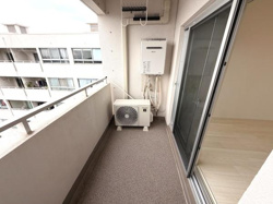 開放感のあるバルコニーです。室外機や給湯器がコンパクトに配置されており空間がしっかり確保されています。隣室との仕切りがシンプルで圧迫感がありません。床面は落ち着いた色合いで整えられています。