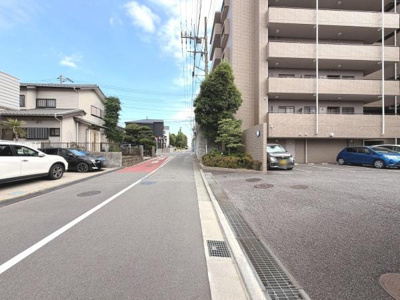 マンション前の道路は幅広く車の出入りもスムーズに行えます。周囲には緑も配置されており利便性と落ち着きを感じられる環境です。建物は清潔感があり使いやすい駐車スペースも確保されています。
