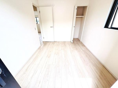 明るい日差しが差し込む洋室です。白を基調とした内装で開放感があります。クローゼット付きで収納スペースも確保されています。居室の扉や窓も使いやすい配置になっています。床の質感も温かみが感じられます。