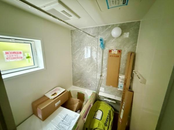 浴室内には明るい窓が設けられており換気にも配慮されています。壁面は落ち着いた色調のパネルで清潔感があります。天井には浴室乾燥機も備わっています。収納スペースとしても活用できる広さです。