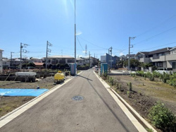 周囲に建物が並ぶ落ち着いた雰囲気の現地写真です。前面道路は広く見通しが良好です。舗装された道路が整備されており車の通行にも安心感があります。建築予定地も隣接している様子が確認できます。