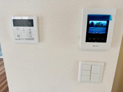 モニター付きインターホンや給湯リモコンがまとめて設置されています。壁にすっきりと収まり操作がしやすい配置です。日常の利便性を高める設備が備わっています。スイッチ類も近くにまとめられています。