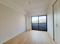 大きな窓から自然光がたっぷり入る洋室です。白を基調とした内装が空間をすっきりと見せています。フローリングの床が明るく清潔感があります。収納付きで片付けもしやすい仕様です。