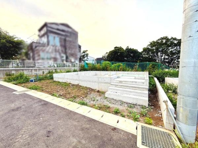 舗装された前面道路に面しており敷地までのアクセスがスムーズです。周辺には緑も多く開放感があります。道路幅も十分に確保されていて車の出入りも便利です。日当たりも良好な現地写真です。