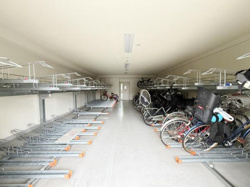 広々とした空間で複数台の自転車を安心して停めることができます。屋内なので天候による影響も受けにくく利用しやすい環境です。ラックが上下2段式で効率よく収納できます。通路も十分な幅が確保されています。