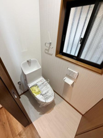明るい空間に設置されたトイレです。窓からの採光があり清潔感が感じられます。シンプルなデザインで使いやすさが意識されています。ペーパーホルダーやリモコンが壁付けで空間を広く利用できます。