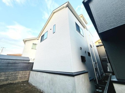 外壁の明るい色が特徴的な外観です。しっかりとした基礎が建物全体を支えています。複数の窓があり室内への採光にも配慮されています。近隣との距離も確保されていてプライバシーが保たれやすい設計です。