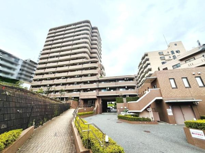 落ち着いた色合いの外観が特徴のマンションです。エントランスまでのアプローチが整備されており手すりも設置されています。複数の建物が連なるデザインが印象的です。周囲の建物との調和が感じられます。