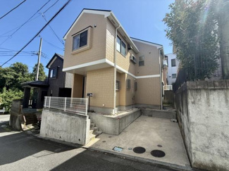 明るい外観が印象的な住宅です。広々とした駐車スペースがあります。高低差を活かした敷地設計が特徴です。周囲が開けた立地で開放感があります。落ち着いた色合いで馴染みやすい外観です。