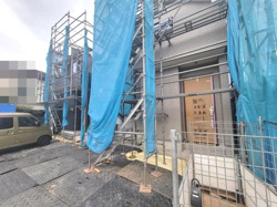 建築中の外観が確認できる写真です。足場がしっかり組まれており工事の進行状況がわかります。新築ならではの清潔感を感じられます。現場の様子がしっかりと写されています。工事現場の安全対策も施されています。