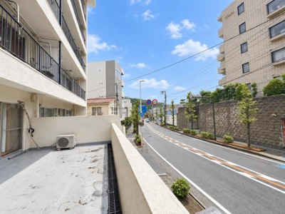 広々としたバルコニーから道路を見渡せる現地からの眺望です。周囲はマンションや緑もあり開放感が感じられます。晴れた日は青空が広がり明るい雰囲気が特徴的です。