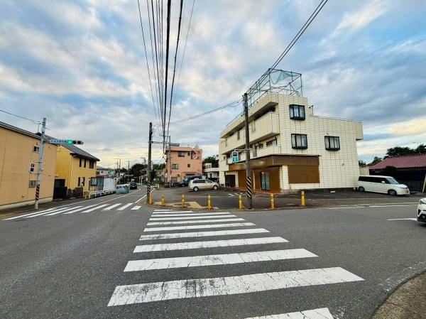 前面道路は幅が広く車両の出入りもしやすい配置です。周辺には建物が整然と立ち並び視界が開けています。交差点が近く交通の流れも分かりやすい環境です。