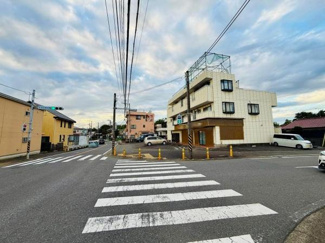 前面道路は幅が広く車両の出入りもしやすい配置です。周辺には建物が整然と立ち並び視界が開けています。交差点が近く交通の流れも分かりやすい環境です。