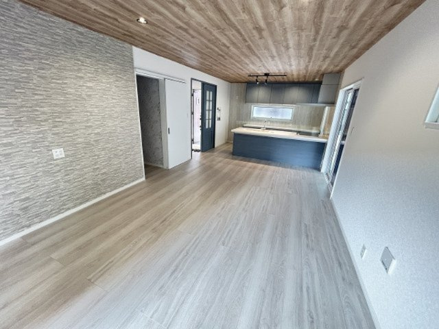 木目の天井×石目調クロスの組み合わせが映えるLDK。キッチンは空間に溶け込むシックなネイビーを採用。