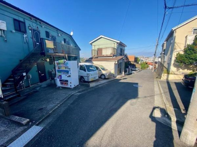 日当たりの良い前面道路で明るさが魅力的な現地の雰囲気を感じられます。道路幅が広く車の出入りもスムーズに行えそうです。周辺には自動販売機もありちょっとした買い物にも便利です。