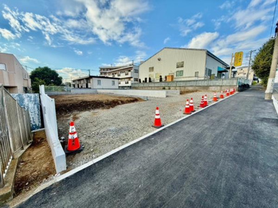 現地の写真からは広々とした土地の様子がうかがえます。周囲の建物との距離感も適度で安心感のある環境です。舗装された前面道路がアクセスの良さを感じさせます。