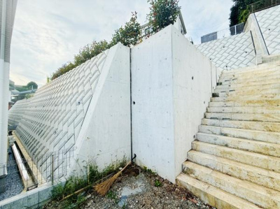 コンクリートの壁と階段がしっかりと造られており安心感を感じられます。階段も広めで昇り降りしやすい設計です。周囲の緑もアクセントとなっており落ち着いた雰囲気です。手入れされた外構が印象的です。