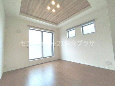 天井のデザインが特徴的な洋室です。大きな窓が複数あり明るい空間を演出しています。床は木目調で落ち着いた印象です。照明もアクセントになっています。