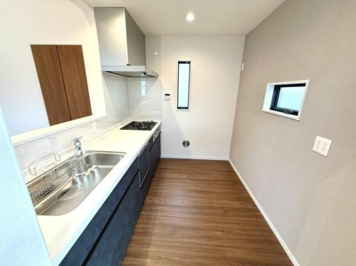 シンプルなデザインのキッチンです。窓があり明るさを感じられます。コンロ・シンクともにまとまりのある配置です。使い勝手の良さが特徴です。すっきりとした雰囲気で日常使いに適しています。
