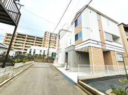 現地の建物はすっきりとした外観が印象的です。前面道路は幅員があり車の出入りがしやすく感じられます。周辺にはマンションなども立ち並び住宅街の落ち着いた雰囲気です。