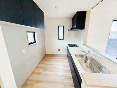 シンプルで清潔感のあるキッチンです。床は明るい色合いで空間全体が広く感じられます。窓があり自然光を取り入れやすい造りです。作業台や収納スペースもすっきりまとまっています。