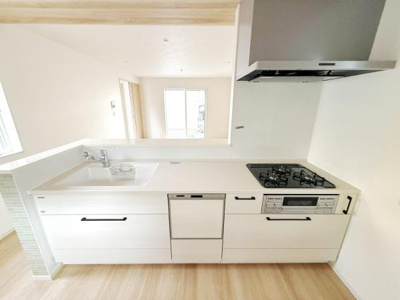 シンプルで清潔感のあるキッチンです。広々としたワークトップが特徴的です。収納スペースも豊富に用意されています。ガスコンロや換気扇もしっかり備えられています。開放感のある空間が広がっています。