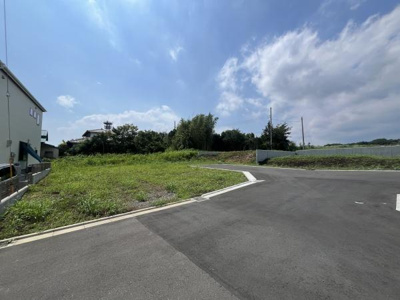 現地の前面道路は広々とした印象で進入や出入りがしやすい配置となっています。周辺には開放感のある景観が広がり視界が抜けているのが特徴です。隣接する建物も少なくゆとりを感じさせる現地写真です。