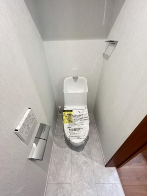 シンプルなデザインのトイレでお掃除がしやすい空間です。床は明るい色調で全体的にすっきりとした印象です。手洗い付きのタンクも備えています。収納やペーパーホルダーも設置されており使い勝手が良い仕様です。