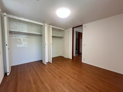 広々としたクローゼットが二つ備え付けられており収納力に優れています。シンプルなデザインで使いやすく室内がすっきりと整います。床は温かみのある色合いで明るい照明が空間を引き立てます。