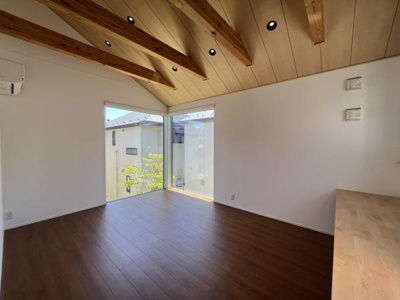 天井の木目と梁が印象的な洋室です。大きな窓からは自然光がしっかりと入ります。床の素材感も温かみを感じさせます。机が備え付けられており使い勝手に配慮されています。角部屋ならではの開放感も魅力です。