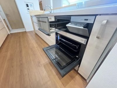 キッチンには使いやすいビルトイン型の設備が整っています。収納スペースも豊富に設けられておりすっきりとした印象です。床は木目調であたたかみがあります。お手入れがしやすいカウンターが特徴です。