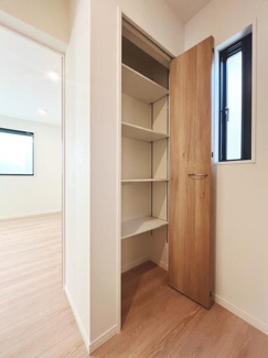 扉付きの収納スペースが設けられており室内をすっきりと保てます。収納内部は棚板が複数あり整理整頓しやすい設計です。ナチュラルな木目調の扉が空間にやさしい印象を与えています。
