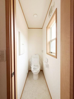 明るい窓付きのトイレは採光性があり換気もしやすい設計です。シンプルな内装でお手入れがしやすい空間になっています。快適にお使いいただける広さが確保されています。壁面収納も設置されています。