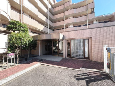 エントランスは広々とした設計で出入りがしやすいです。タイル張りの外観が上品な印象を与えます。木々の緑がアクセントになっています。ガラスブロックの窓が外観に個性をプラスしています。