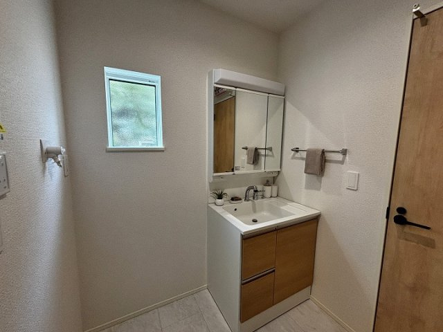 木目調の扉の洗面化粧台です。
身支度のしやすい大型の鏡と明るい照明が魅力です