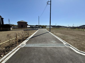 広々とした現地土地写真です。周辺には新しい建物や緑があり開放感が特徴です。道路からもアクセスしやすい立地で周囲も整った印象です。整地された状態で工事車両も見られます。