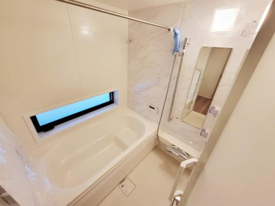 明るい窓付きのバスルームで清潔感のある空間が広がっています。壁のデザインや大きめの鏡が空間をすっきりと見せています。浴槽はゆとりのあるサイズで使い勝手の良いレイアウトです。