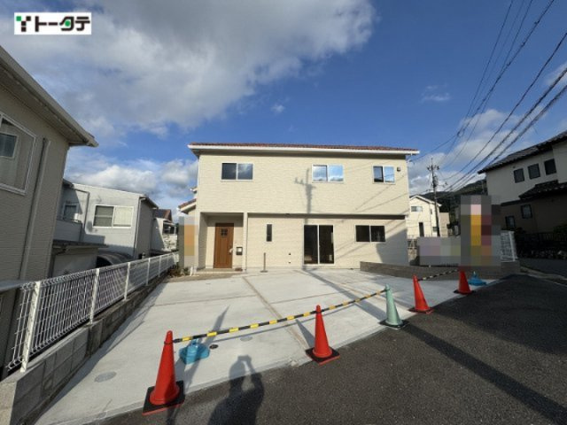 明るいベージュの外壁にあたたかみのある木目調の玄関ドアがアクセント。駐車もスムーズに行えるスペース。