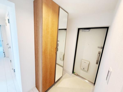 玄関には大きなシューズボックスと全身鏡が備え付けられており身支度にも便利です。すっきりとした明るい雰囲気で清潔感のある空間です。扉や壁の色合いも調和が取れています。セキュリティが確保された玄関です。