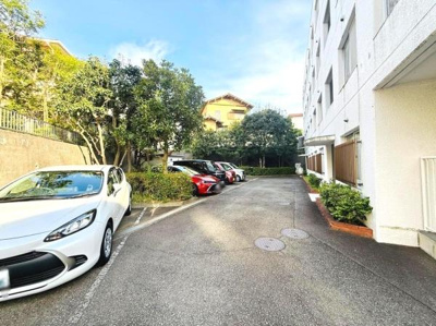 建物横に配置された駐車場は車両の出し入れがしやすい造りです。敷地内の植栽が周囲を囲み明るい雰囲気を演出しています。平坦な舗装路が歩きやすく日常利用にも便利です。