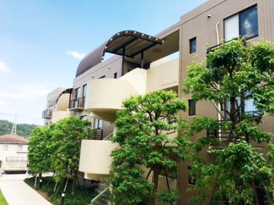 明るい外観とゆとりのある共用部分が印象的な建物です。緑豊かな植栽が並び爽やかな雰囲気が感じられます。曲線が特徴的な階段デザインも目を引きます。開放感のある環境が魅力の一つです。