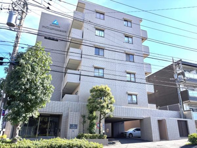 明るい外観が特徴のマンションです。落ち着いた色合いの外壁が印象的です。エントランス周辺も緑があり清潔感があります。複数のバルコニーからの光も豊かです。駐車場スペースが建物内に確保されています。