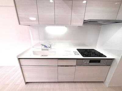 シンプルで統一感のあるカラーが清潔感を演出します。ワークトップは広く手元の作業がしやすい設計です。吊戸棚も備わっており収納力に配慮されています。ガスコンロとシンクの配置が使いやすさを高めています。