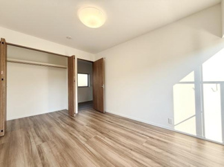広々とした収納スペースが備わっています。床とドアのウッドカラーが温かみを感じさせます。部屋全体が明るく余裕のある空間となっています。クローゼット扉が開き戸で使い勝手も良好です。