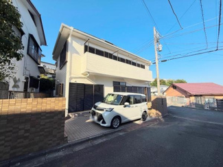 白を基調とした外観が清潔感を演出しています。広いバルコニーが印象的な建物です。駐車スペースも確保されています。前面道路からのアクセスも便利です。シンプルで落ち着いたデザインが特徴です。