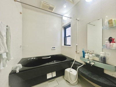 黒を基調としたバスタブが目を引く空間です。壁には手すりが設置されており安心して利用できます。窓も付いており換気に配慮されています。広々とした印象の浴室です。