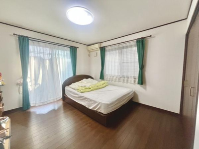 二面に窓があり自然光が射し込む明るい寝室です。収納スペースも扉付きで整理がしやすい印象です。床は落ち着いた色合いのフローリングで清潔感があります。