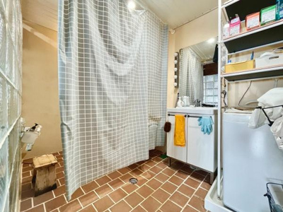 広々とした洗面所で収納棚が充実しています。洗濯機スペースも確保されており使い勝手の良い空間です。明るい照明と大きな鏡があるので日常の身支度にも便利です。床はタイル張りでお手入れがしやすくなっています。